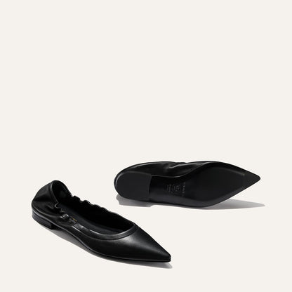A pair of Margaux’s The Roma - Black Nappa ballet flats: one upright, displaying the top and side, the other on its side to show the sole and heel, all set against a plain light background.