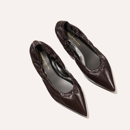 The Roma - Cocoa Crinkle Patent by Margaux are womens pointed-toe ballet flats in dark brown crinkle patent leather with ruched detailing, shown against a light background.