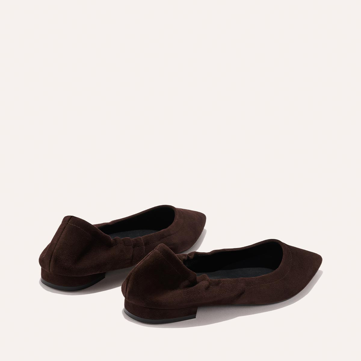 The Roma - Espresso Suede by Margaux: dark brown, pointed-toe suede ballet flats with subtle ruching at the heel, shown on a light neutral background.