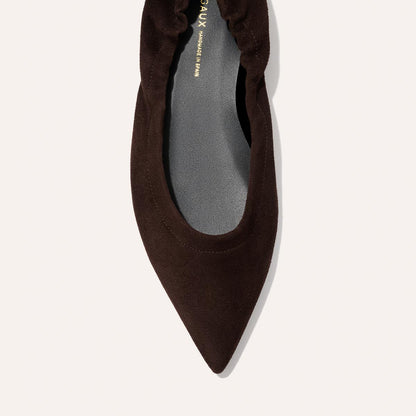 A close-up top view of Margaux’s The Roma - Espresso Suede flat, featuring a dark brown, pointed toe, ruched elastic back, and soft matte finish.