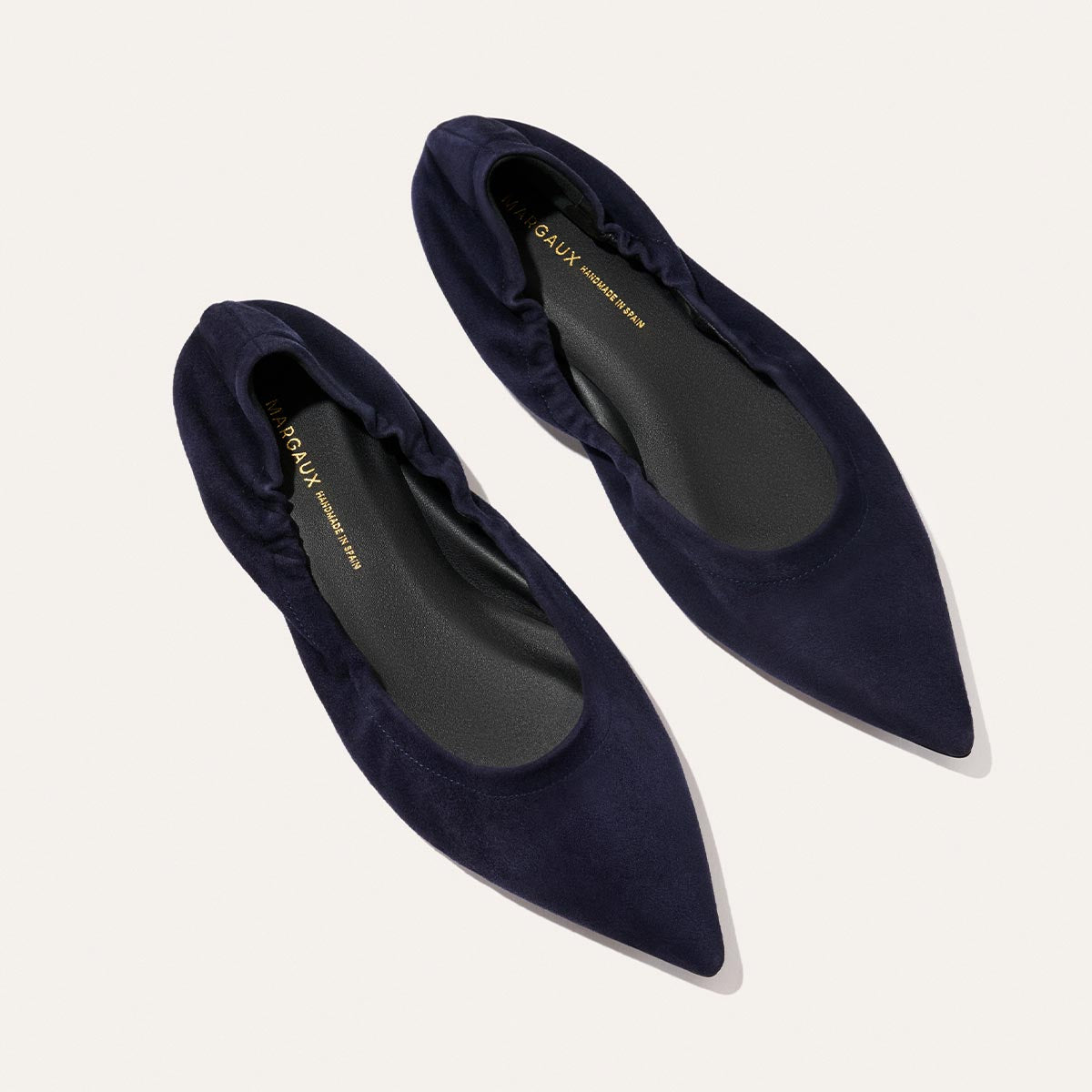 A pair of Margaux’s The Roma - Indigo Suede pointed-toe ballet flats with elasticized edges, shown from above on a light background.