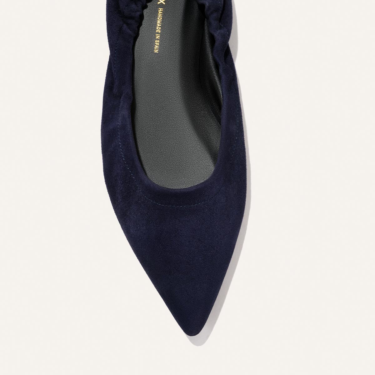 A top view of The Roma - Indigo Suede by Margaux, a sophisticated ballet flat in rich indigo suede, featuring a pointed toe, ruched heel, and black insole on a light background.