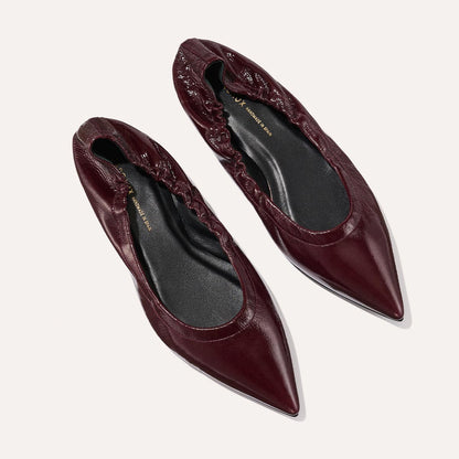 The Roma - Merlot Crinkle Patent by Margaux: chic pointed-toe ballet flats in burgundy with gathered elastic edges and black insoles, shown on a light background.
