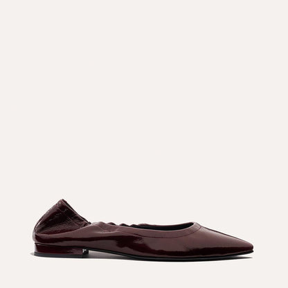 The Roma - Merlot Crinkle Patent by Margaux: a dark burgundy patent leather pointed-toe ballet flat with a low heel and gathered heel detail, showcased on a plain light background.