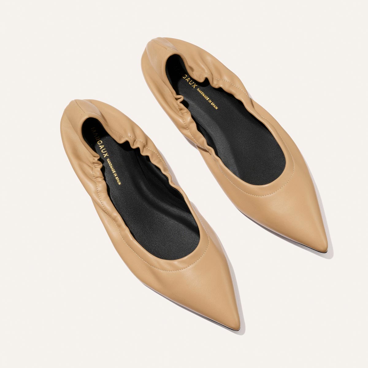 The Roma - Praline Nappa by Margaux: tan pointed-toe flats with gathered, elasticized edges and black insoles, shown on a light background.