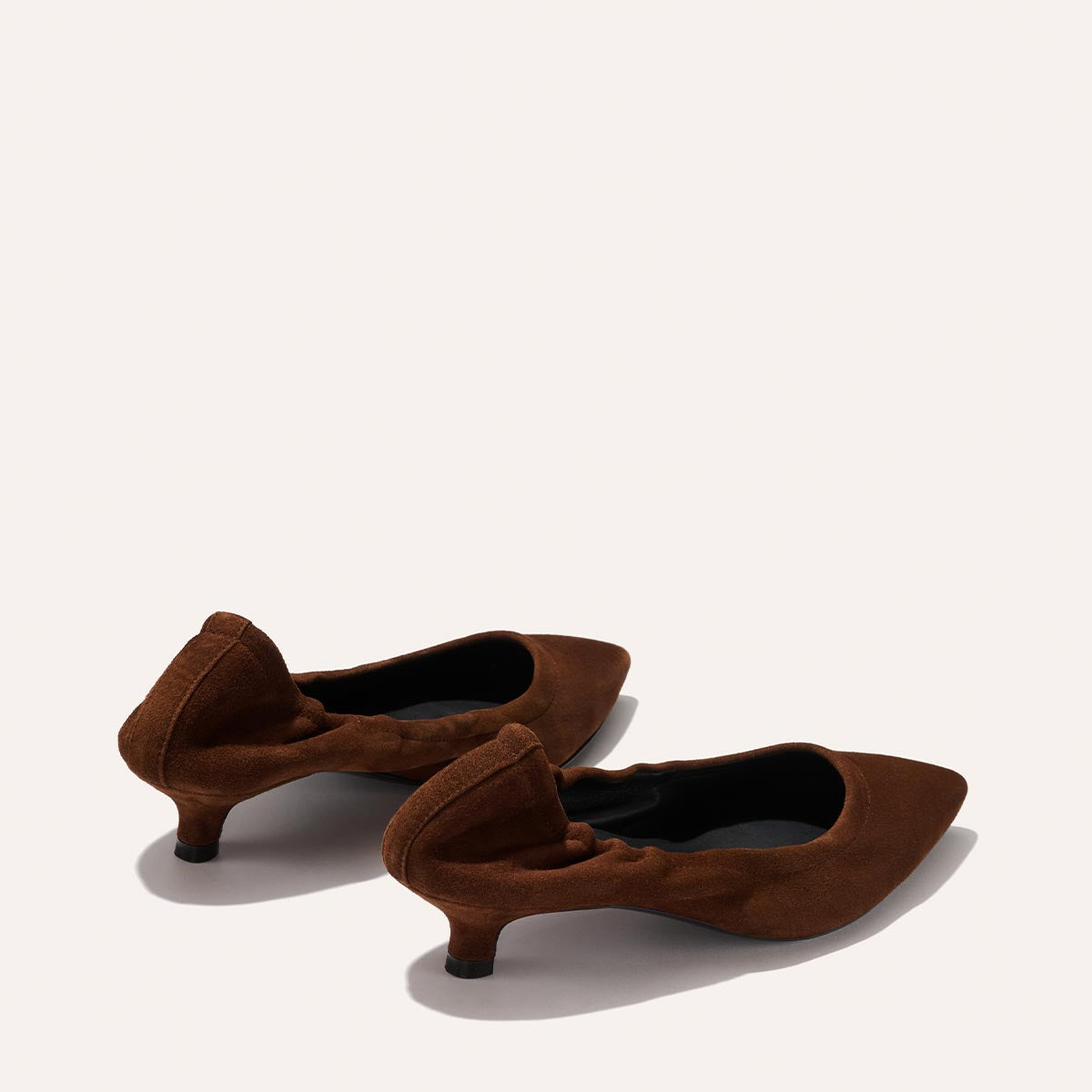 The Margaux Roma 40 - Ganache Suede are brown, suede, pointed-toe flats with a walkable heel and ruched heel detail, shown on a light background.