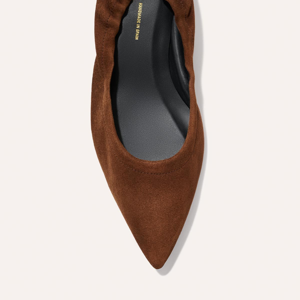 Top view of The Roma 40 - Ganache Suede by Margaux, a brown suede pointed-toe flat with a black insole and gathered detailing, set against a light background.