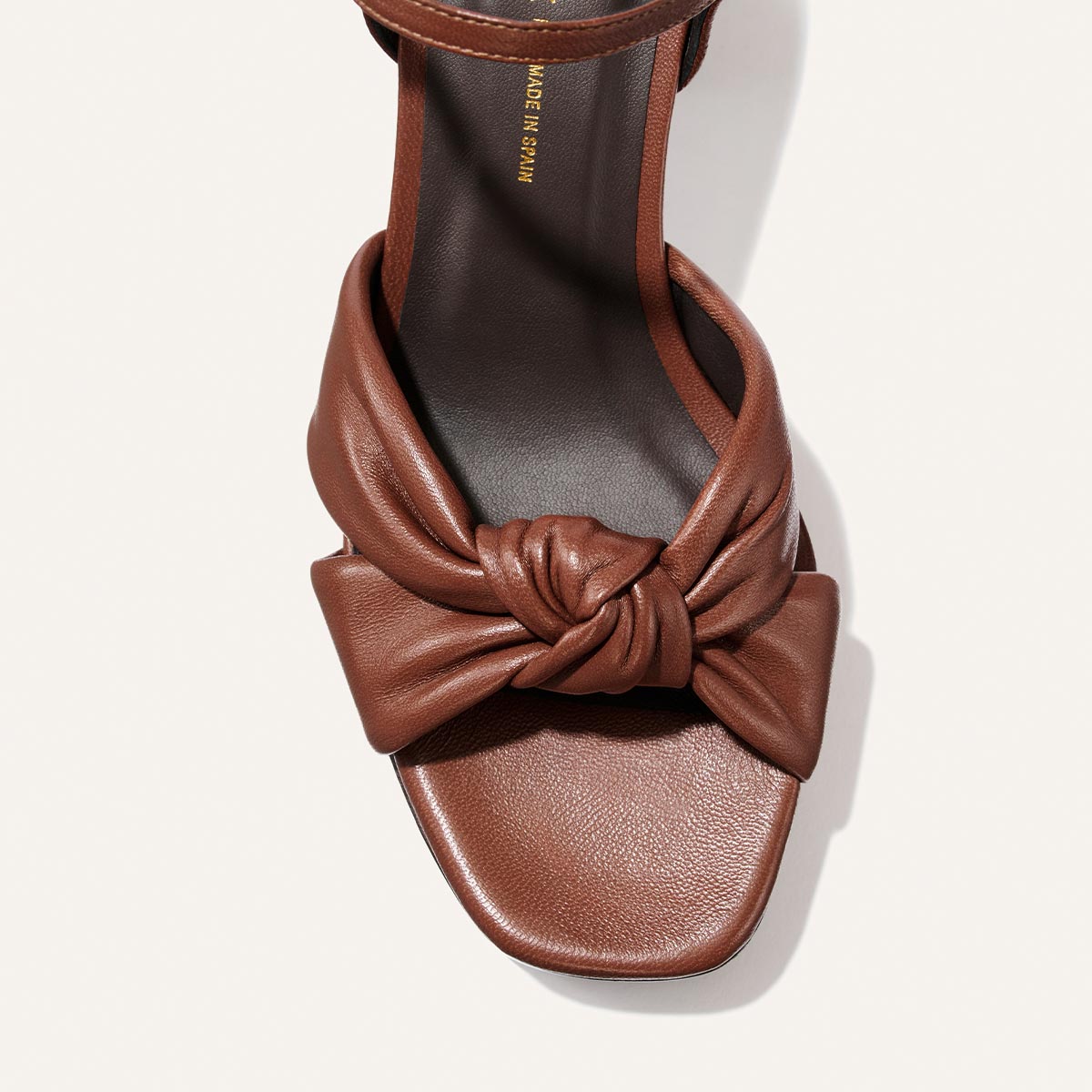 The Sabine Platform in Brandy Glove Nappa by Margaux, featuring a knotted strap detail over the toe and a square-shaped toe box, is shown from a top-down perspective on a light background.