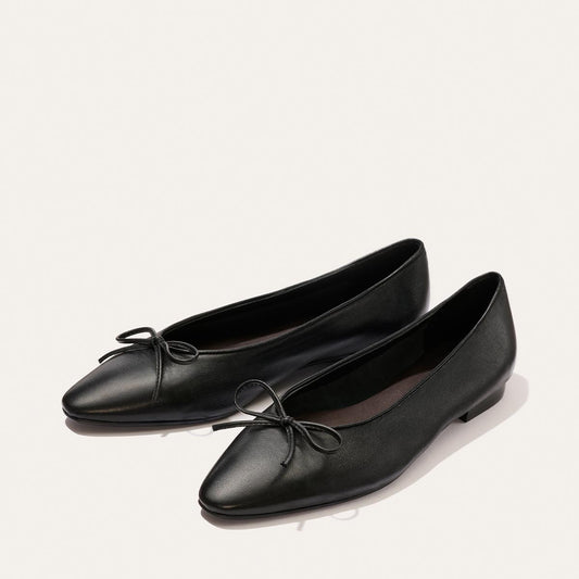 The Salamanca - Black Nappa ballet flats by Margaux, featuring a pointed toe and delicate bows on the front, are displayed on a light background.