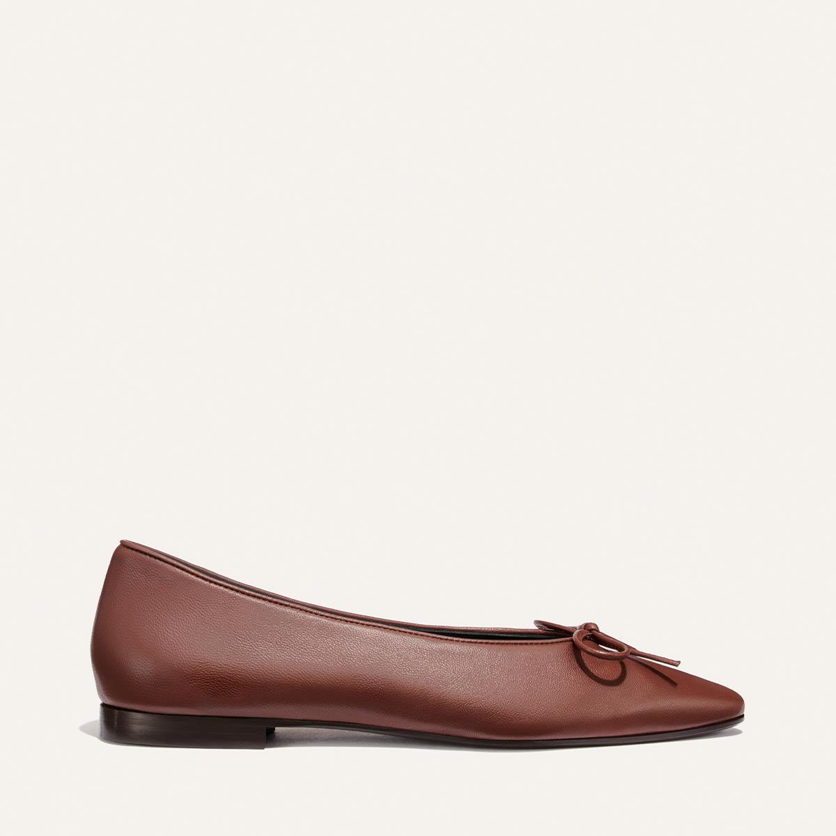 A single Brandy Nappa “The Salamanca” ballet flat by Margaux featuring a pointed toe, small bow detail on the toe, low heel, and photographed against a plain background.