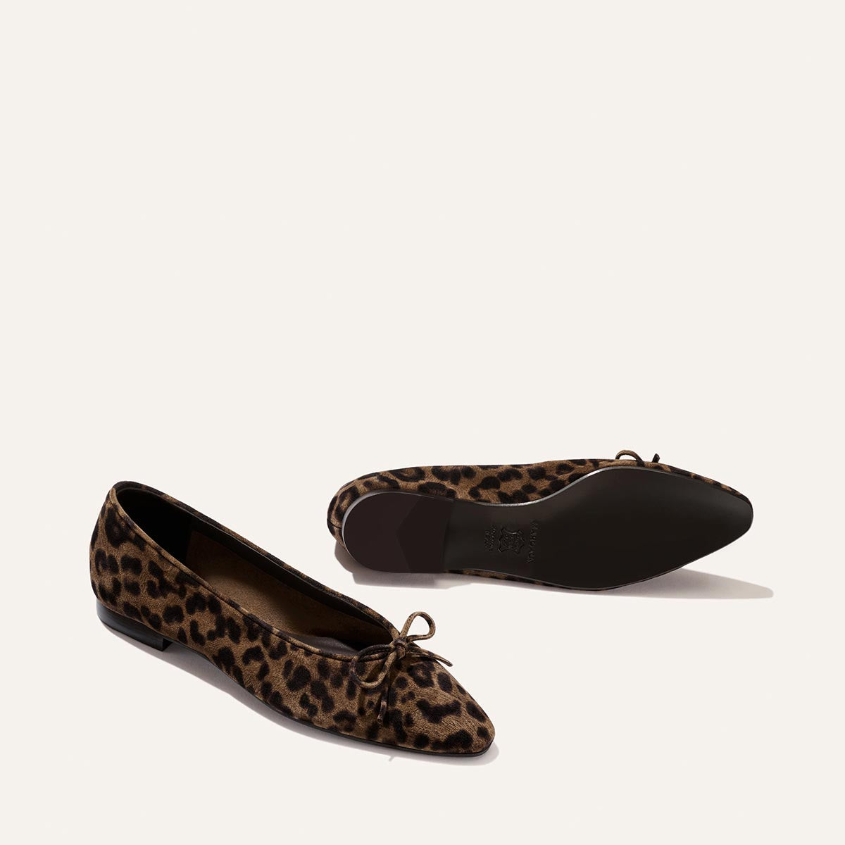 Two "The Salamanca - Brown Leopard Suede" ballet flats by Margaux are displayed on a light background; one shoe stands upright while the other rests on its side, revealing the sole.