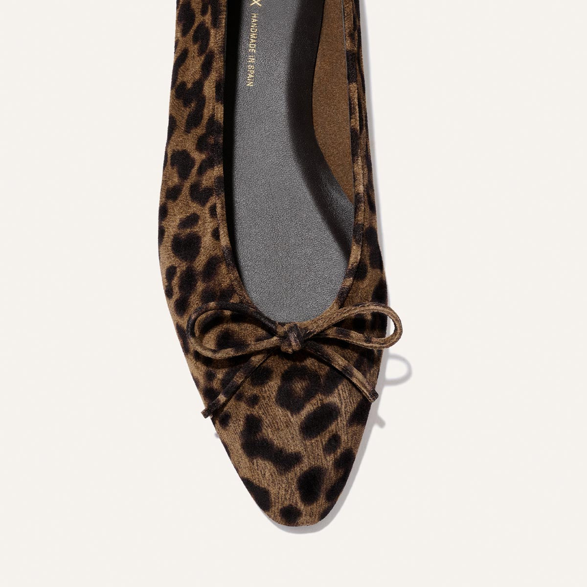A close-up of The Salamanca - Brown Leopard Suede flat by Margaux, featuring a pointed toe, leopard print suede, and a delicate front bow, photographed from above on a plain light background.