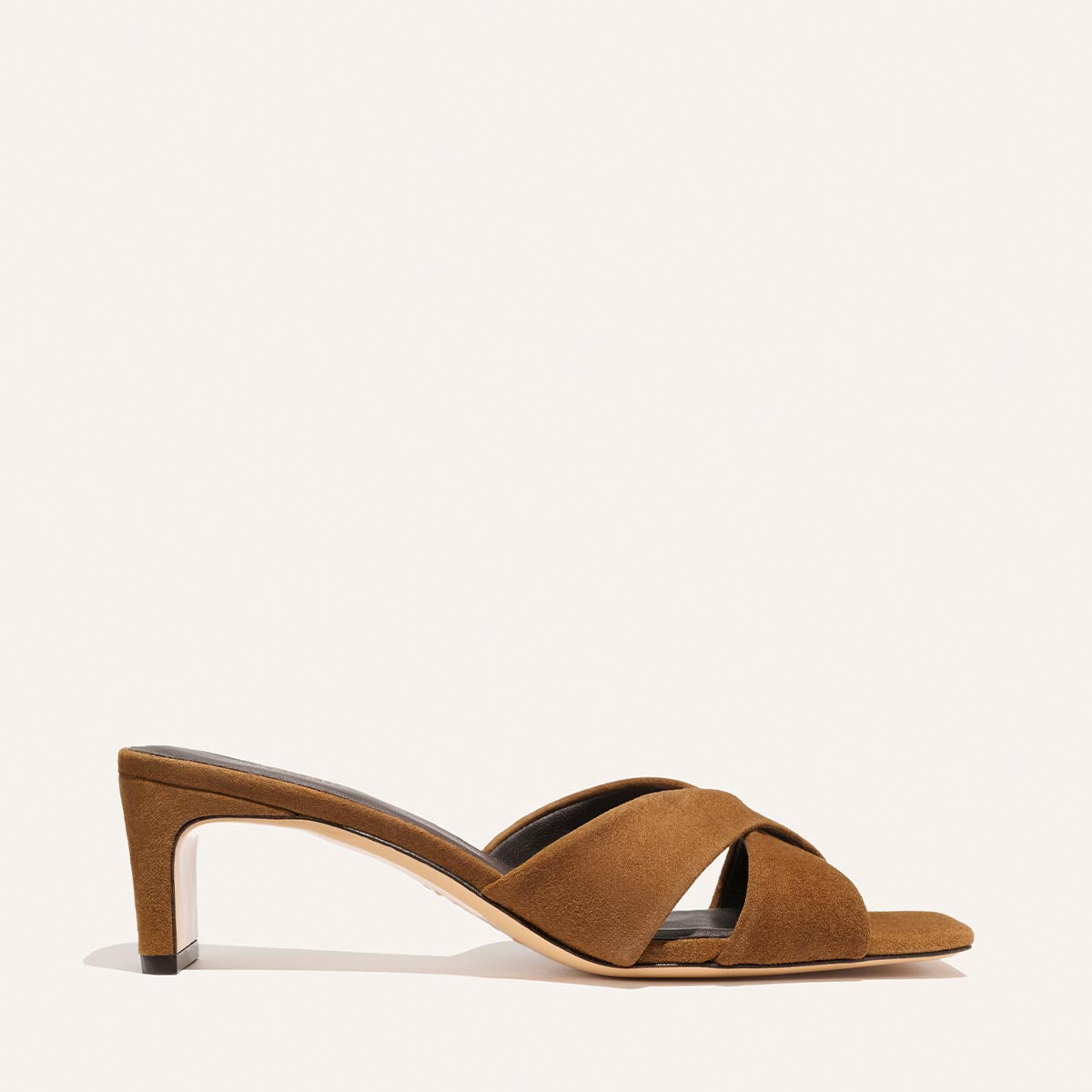 The Selene 50 - Nutmeg Suede by Margaux features a brown suede heeled sandal with open toes, crisscross leather straps, and a low slim heel, displayed in side profile against a plain light background.