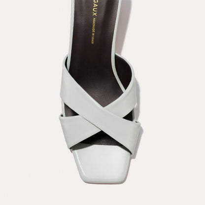 Light blue sandal with criss-cross straps on a light gray background