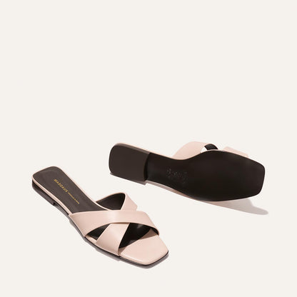 Pair of light pink sandals with a black sole on a white background