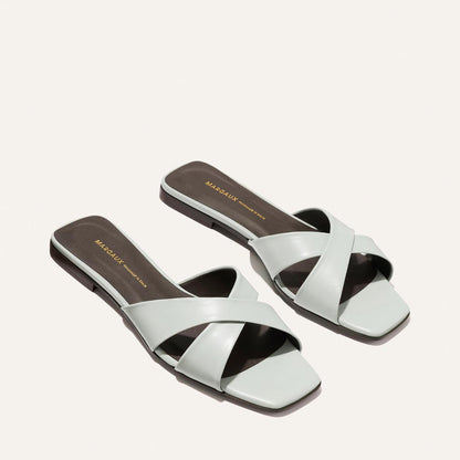 Pair of light blue sandals with criss-cross straps on a white background
