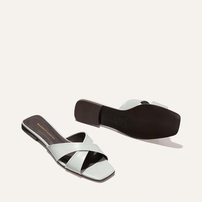 Pair of light blue sandals with black soles on a white background