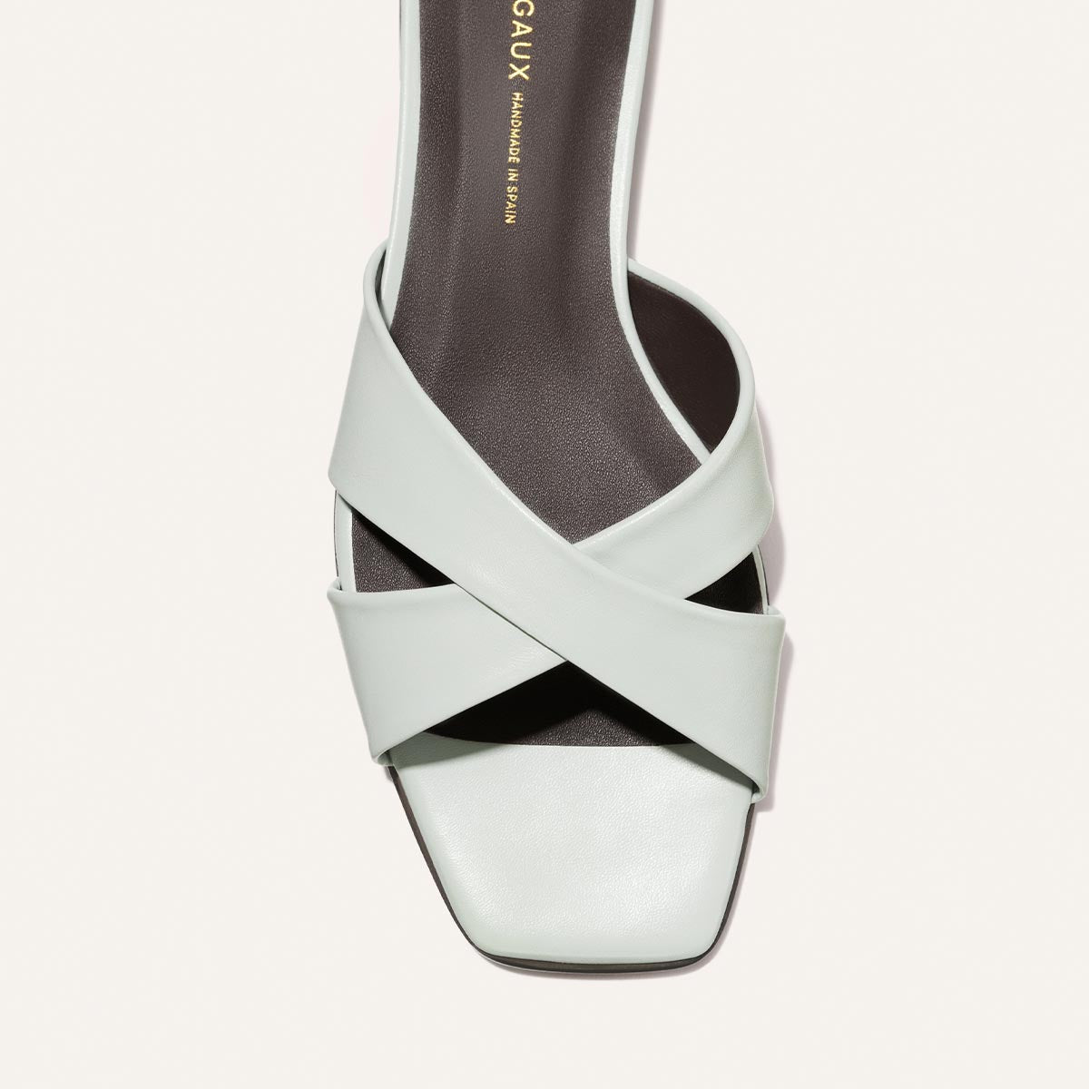 Light blue sandal with criss-cross straps on a light gray background