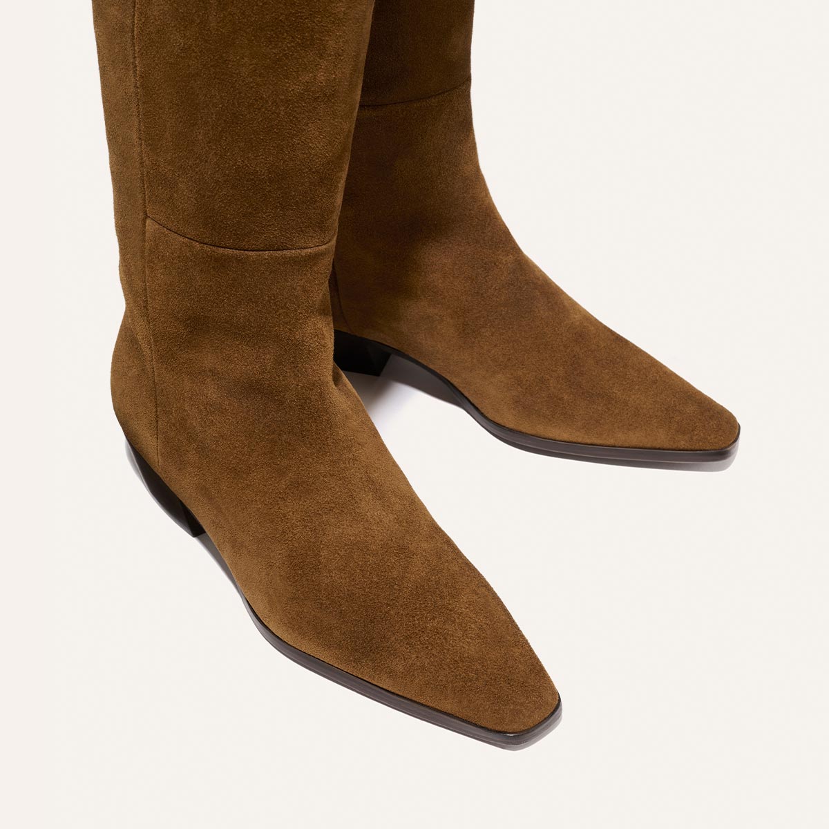 Close-up of The Sierra Knee-High Boot in Cedar Suede by Margaux, featuring pointed toes and low heels, displayed on a light background.