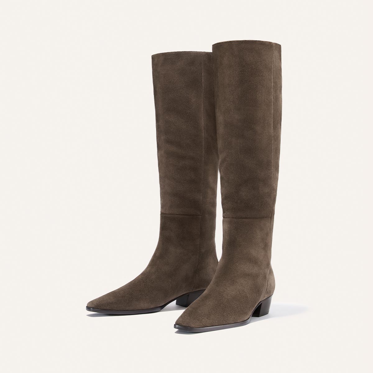 The Sierra Knee-High Boot by Margaux in English Brown Suede is a pair of tall boots featuring low heels, slightly pointed toes, and a simple, elegant design, showcased against a plain light background.