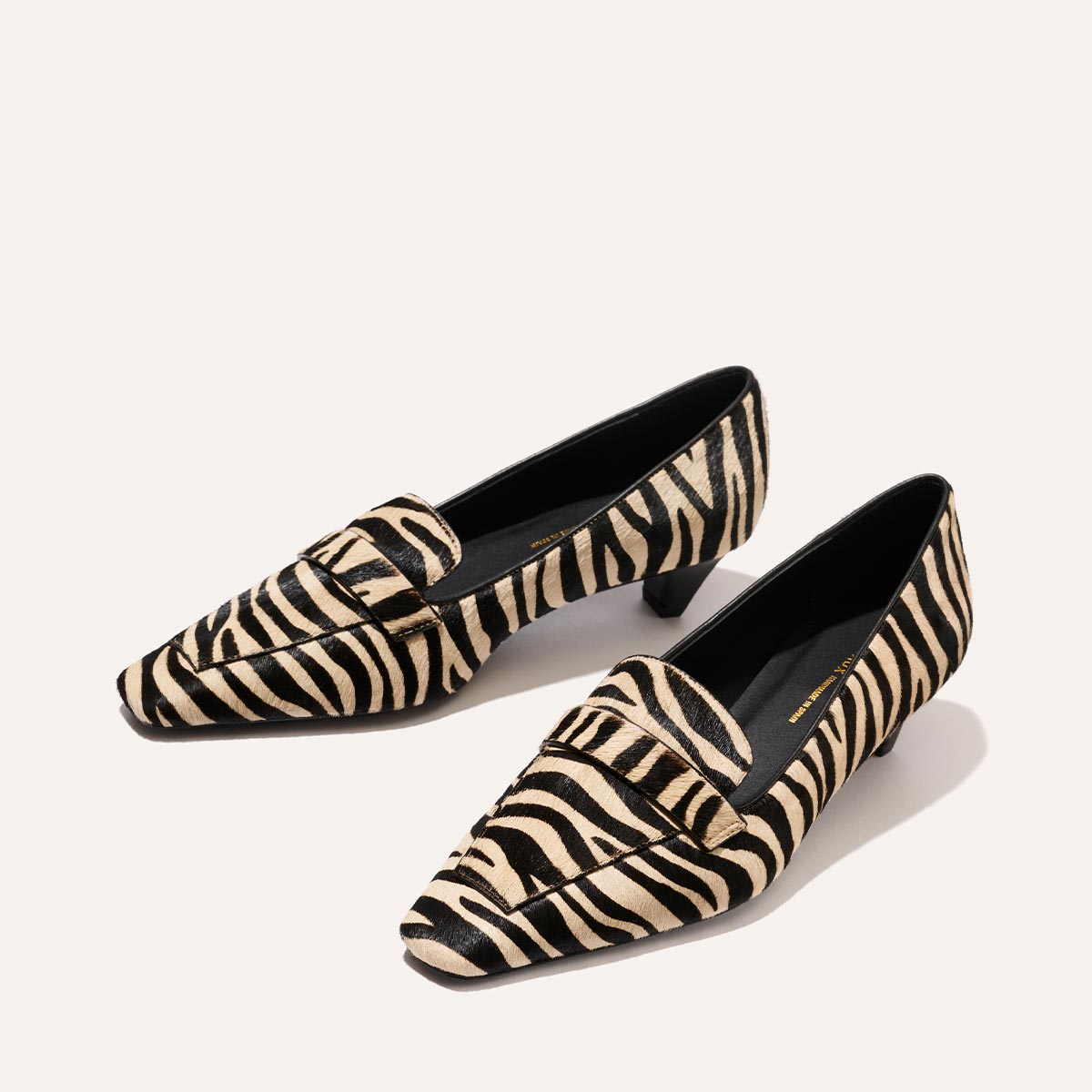 The Sigrid - Tan Zebra Haircalf loafers in tan and black zebra-print with low block heels.