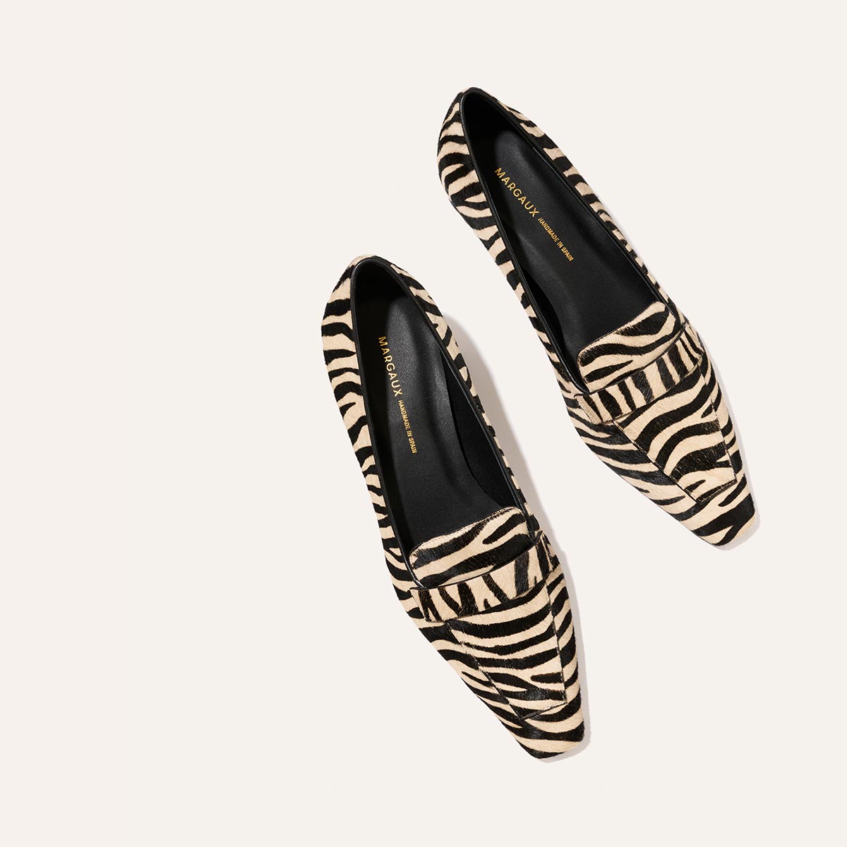 The Sigrid - Tan Zebra Haircalf loafers in a tan and black zebra-striped pattern with square toes.