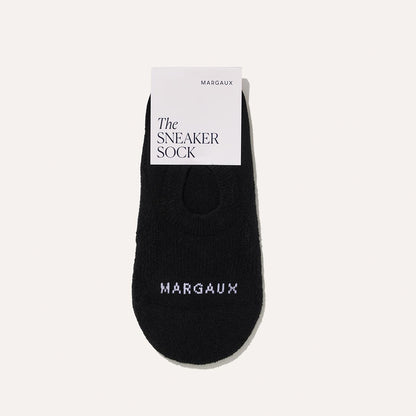 A single black no-show sock with white Margaux text on the toe, shown with a white Margaux The Sneaker Sock label against a light background. Product: The Sneaker Sock - Black by Margaux.