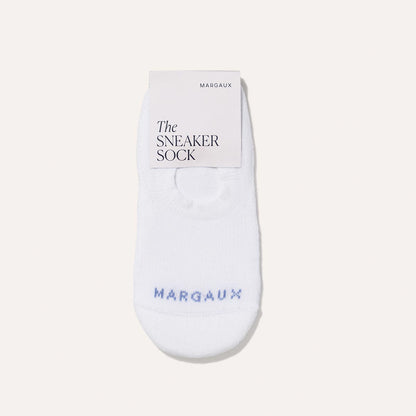 A single white no-show sock from Margaux, labeled The Sneaker Sock – White in blue text, is displayed flat on a light background with a tag at the top reading Margaux The Sneaker Sock for ultimate comfort.