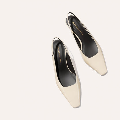 A pair of ecru crinkle patent Sofia Sling shoes by Margaux, featuring a square toe, subtle micro heel, black insoles with gold ‘Margaux’ branding—displayed on a light background.