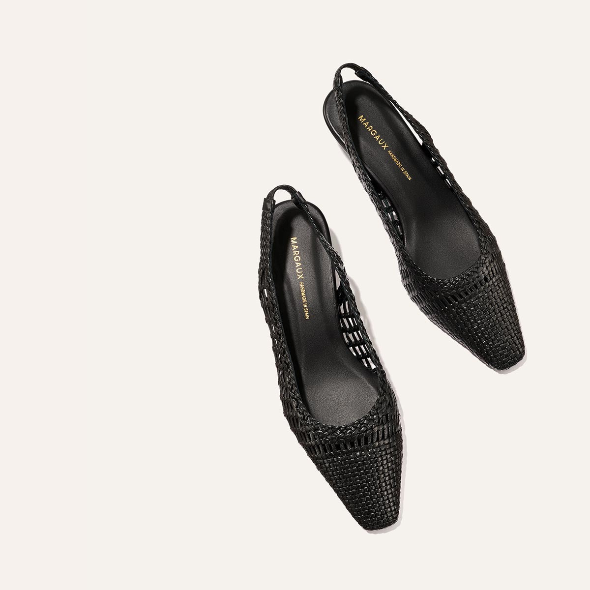 The Sofia Sling - Black Woven Leather by Margaux, a pair of pointed-toe slingback flats, shown on a light beige background.