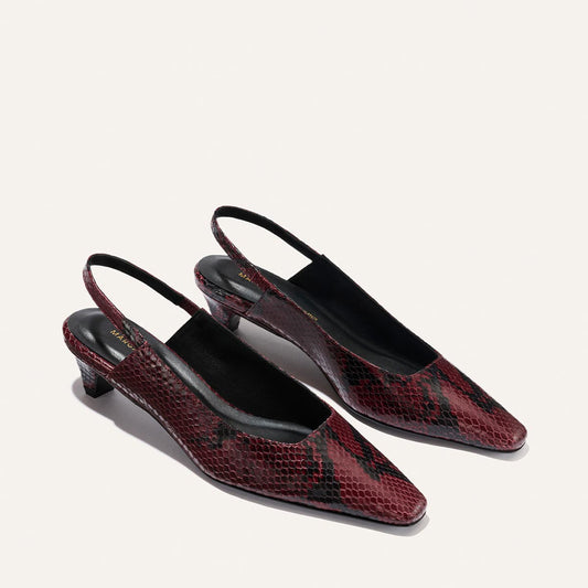 The Sofia Sling - Burgundy Python Embossed by Margaux: a pair of pointed-toe, red and black snakeskin-patterned slingback heels with low square heels, showcased on a light background.