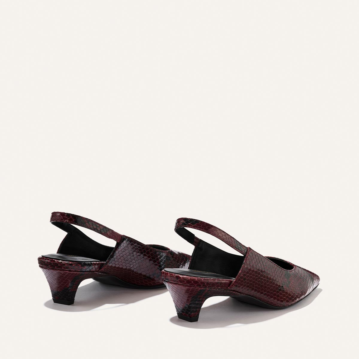 The Sofia Sling - Burgundy Python Embossed by Margaux is a pair of low-heeled, open-back slingbacks in a dark red and black snakeskin pattern, shown on a light background with the back and sides visible.