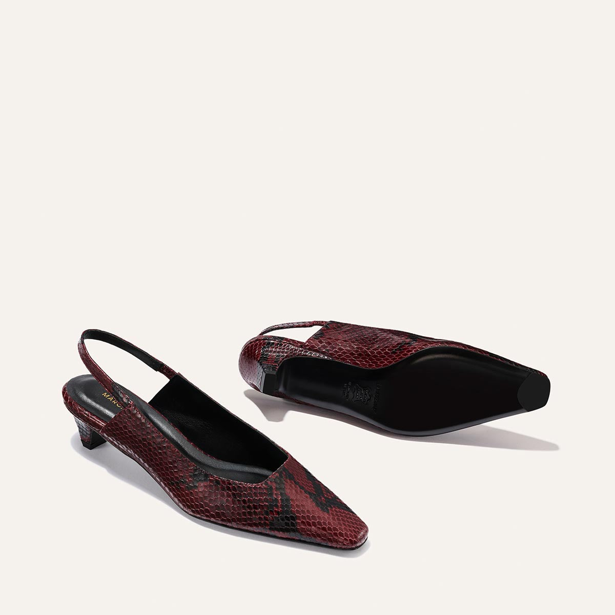 The Sofia Sling - Burgundy Python Embossed by Margaux features a red snakeskin pattern, pointed toes, low kitten heels, black soles, and is displayed against a plain light background.