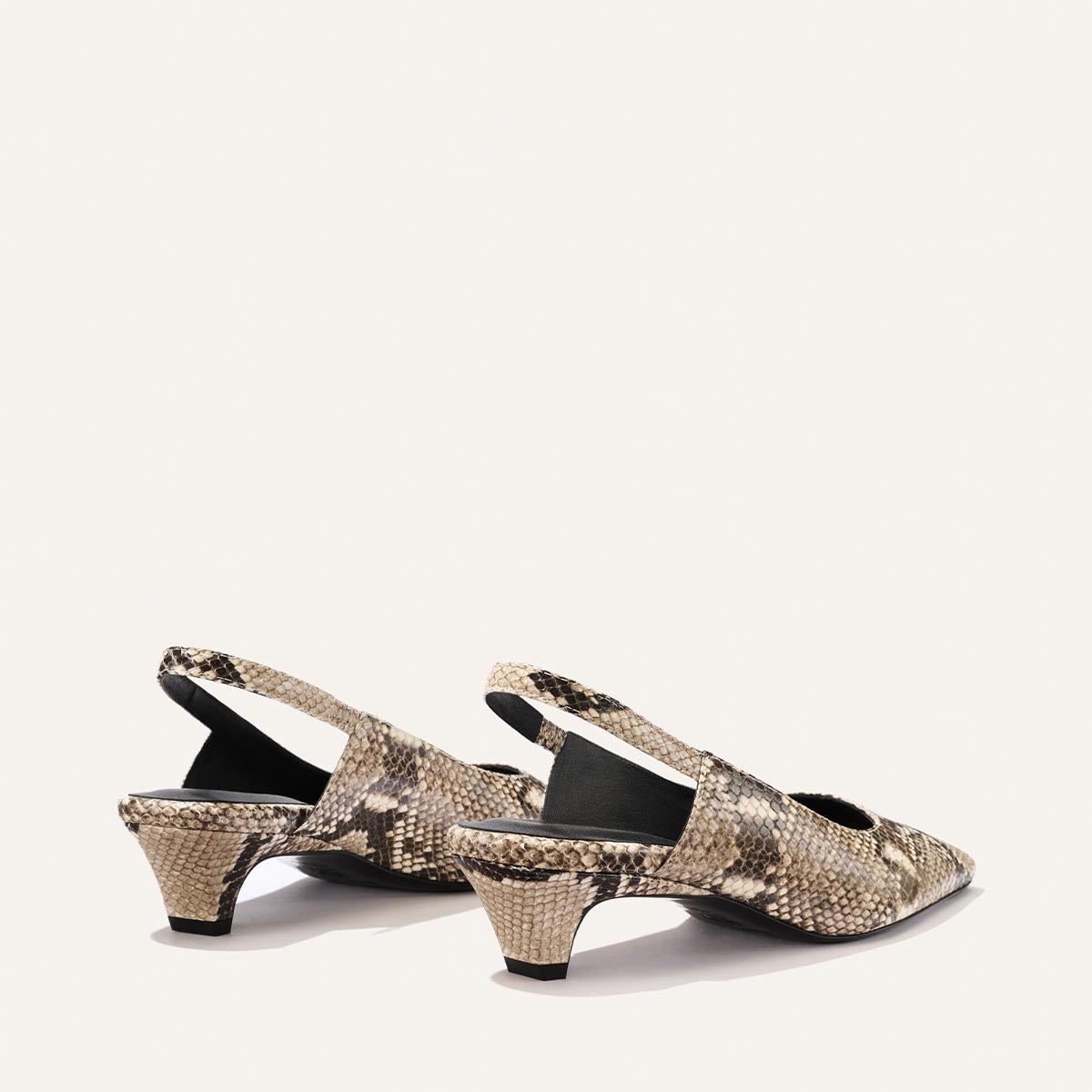 The Sofia Sling by Margaux features a pointed toe and snip nose design, crafted in a natural python-embossed beige and brown pattern with a 1.5" heel, showcased against a plain, light background.