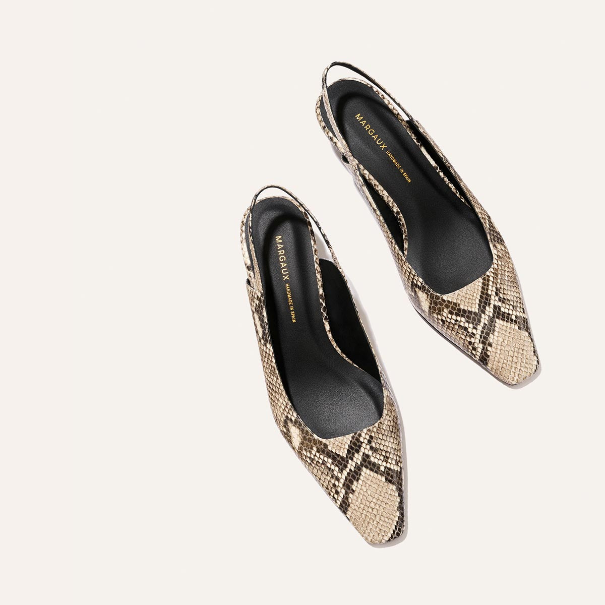 The Sofia Sling - Natural Python Embossed by Margaux is a pair of women's pointed-toe slingback shoes, featuring a striking snakeskin pattern, black insoles, and a chic 1.5" heel, displayed on a light background.