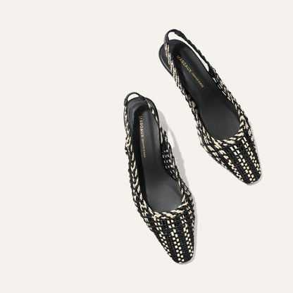 Black and white woven slingback shoes on a light gray background