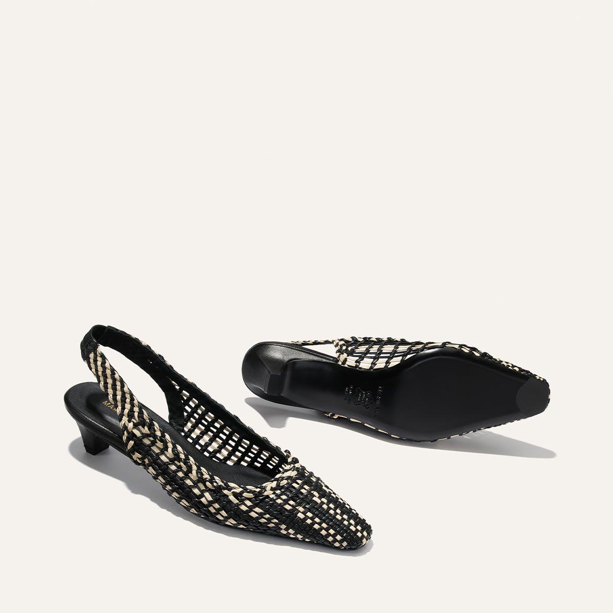 Black and white woven slingback shoes on a light gray background