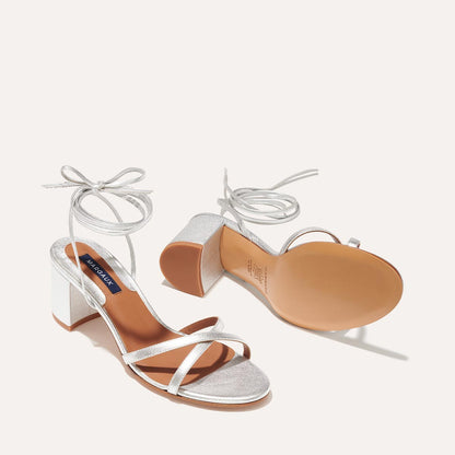 The Soho Sandal in Silver Nappa, featuring thin, flattering straps with a delicate ankle wrap, and a comfortable 2.5-inch block heel.