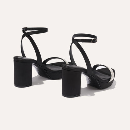 The Stella Platform in Black Satin with Crystals, featuring a sleek strap across the toes and a comfortable 3.5-inch block heel and platform.