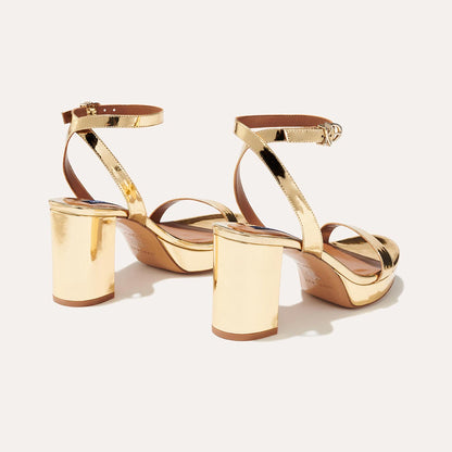 The Stella Platform in Gold Mirror, featuring a sleek strap across the toes and a comfortable 3.5-inch block heel and platform.