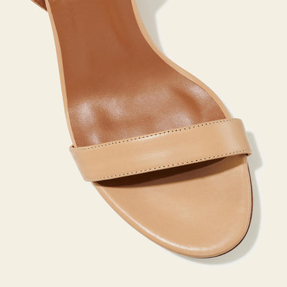 The Stella Sandal in Dune Nappa, featuring a sleek strap across the toes and a comfortable 2.5-inch breasted heel.