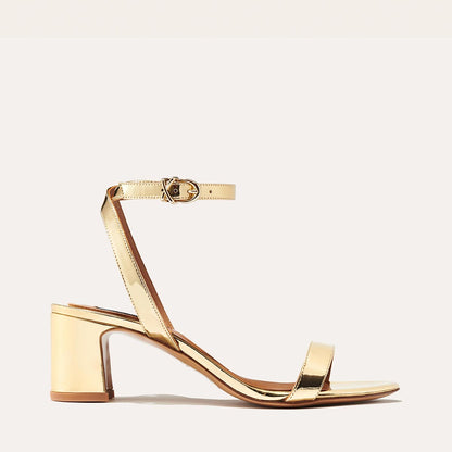 The Stella Sandal in shiny Gold Mirror, featuring a sleek strap across the toes and a comfortable 2.5-inch breasted heel.