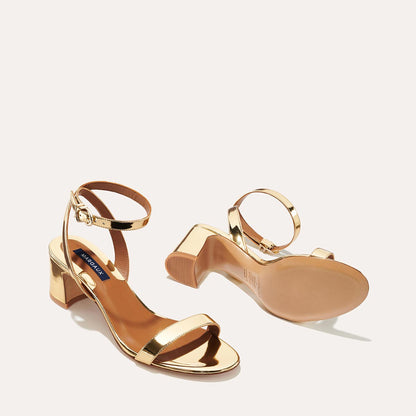The Stella Sandal in shiny Gold Mirror, featuring a sleek strap across the toes and a comfortable 2.5-inch breasted heel.