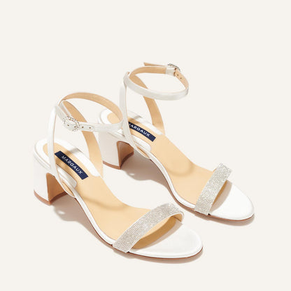 The Stella Sandal in Ivory Satin with crystal embellishment, featuring a sleek strap across the toes and a comfortable 2.5-inch breasted heel.