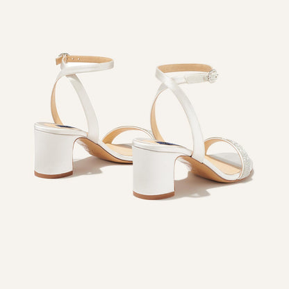 The Stella Sandal in Ivory Satin with crystal embellishment, featuring a sleek strap across the toes and a comfortable 2.5-inch breasted heel.