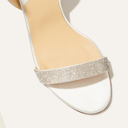 The Stella Sandal in Ivory Satin with crystal embellishment, featuring a sleek strap across the toes and a comfortable 2.5-inch breasted heel.