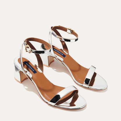 The Stella Sandal in shiny Silver Mirror, featuring a sleek strap across the toes and a comfortable 2.5-inch breasted heel.