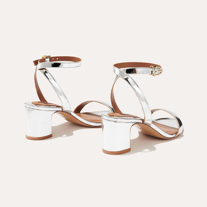 The Stella Sandal in shiny Silver Mirror, featuring a sleek strap across the toes and a comfortable 2.5-inch breasted heel.