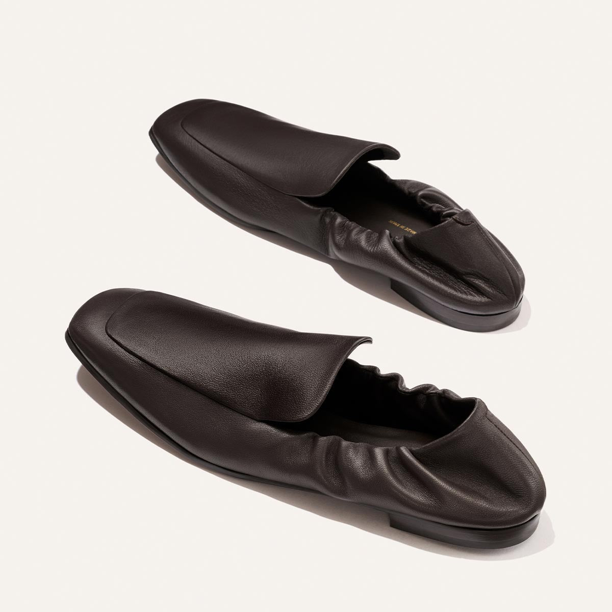 A pair of Margaux's The Studio Loafer in Espresso Nappa, featuring a square toe and elastic heel, is displayed on a light background.