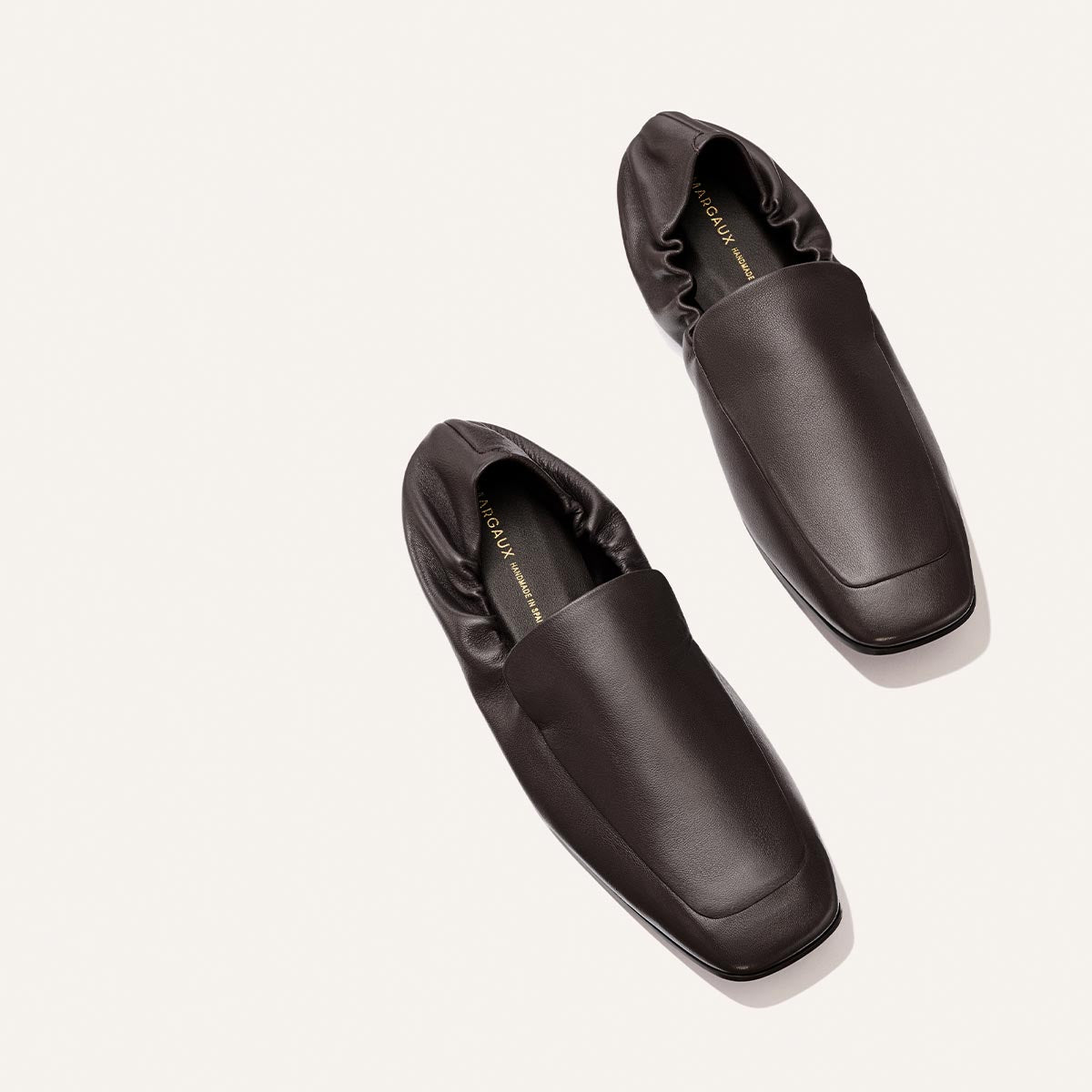 A pair of The Studio Loafer - Espresso Nappa by Margaux, featuring dark brown leather, square toes, and gathered elastic backs, displayed on a light background.